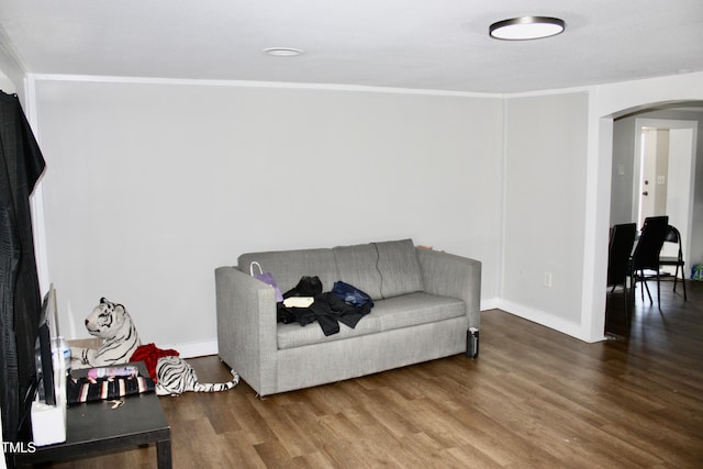 living area featuring arched walkways, wood finished floors, and baseboards