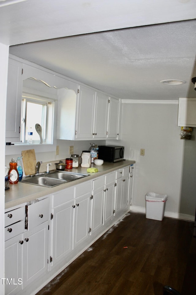 kitchen featuring black microwave, a sink, dark wood finished floors, and white cabinetry