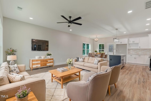 living area with baseboards, visible vents, a ceiling fan, light wood-type flooring, and recessed lighting