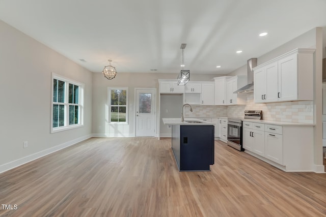 kitchen featuring a sink, wall chimney range hood, decorative backsplash, stainless steel electric range oven, and a center island with sink