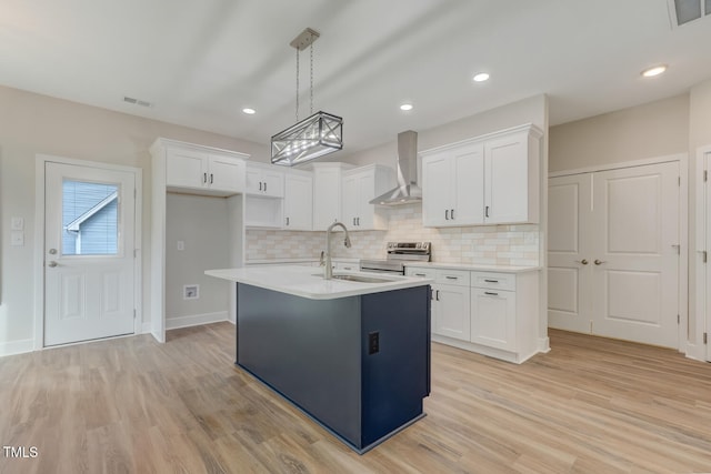 kitchen with a sink, visible vents, white cabinets, wall chimney range hood, and stainless steel electric range