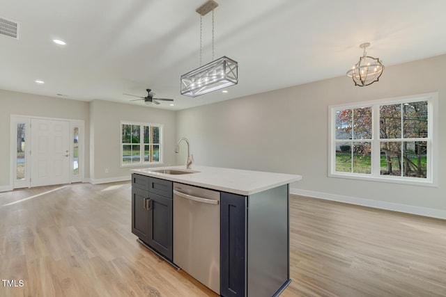 kitchen featuring light wood finished floors, open floor plan, light countertops, stainless steel dishwasher, and a sink