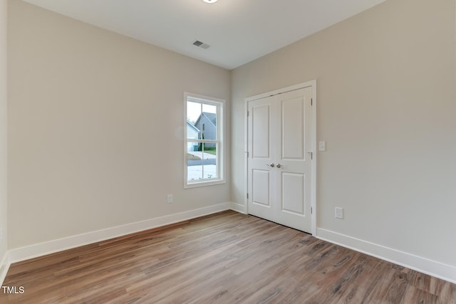 unfurnished bedroom with wood finished floors, visible vents, and baseboards