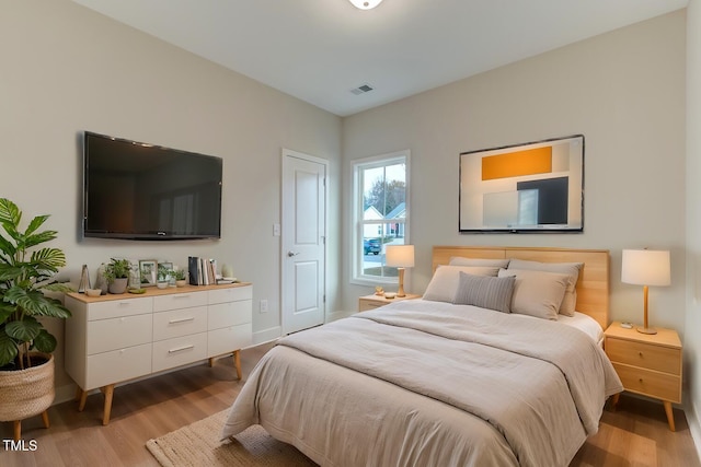 bedroom with light wood finished floors, visible vents, and baseboards