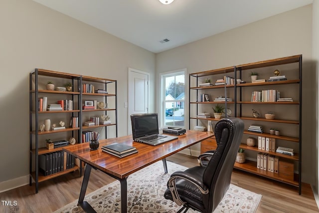 home office with wood finished floors, visible vents, and baseboards