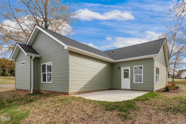 rear view of property with a yard, a shingled roof, and a patio area