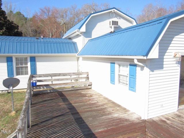 view of property exterior featuring a deck, metal roof, and a gambrel roof