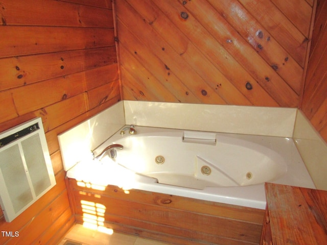 full bathroom with a whirlpool tub, wood walls, visible vents, and heating unit