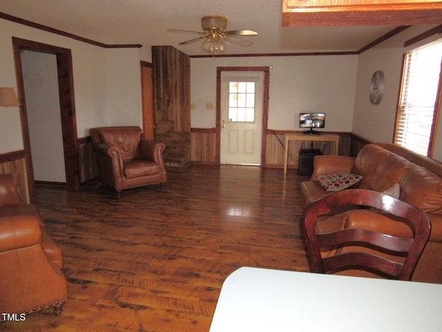 living area with a ceiling fan, ornamental molding, wood finished floors, and a wainscoted wall