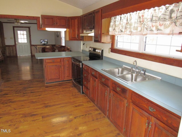 kitchen with light countertops, stainless steel range with electric cooktop, a sink, a peninsula, and under cabinet range hood