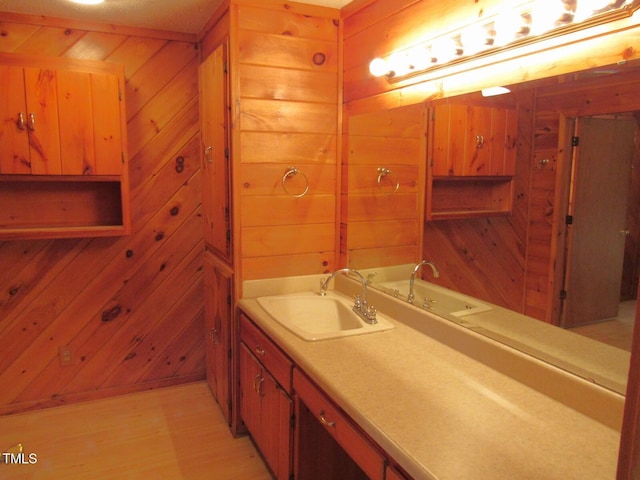 bathroom featuring wood walls, a sink, and wood finished floors