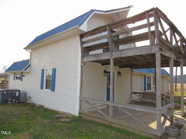 view of side of home featuring metal roof and central AC