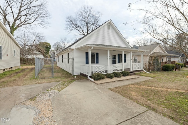 view of front of home with covered porch, a front lawn, fence, and a gate