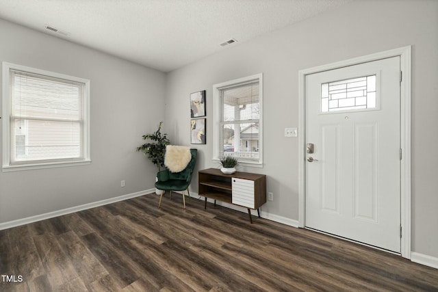 entrance foyer featuring dark wood-style floors, baseboards, visible vents, and a textured ceiling