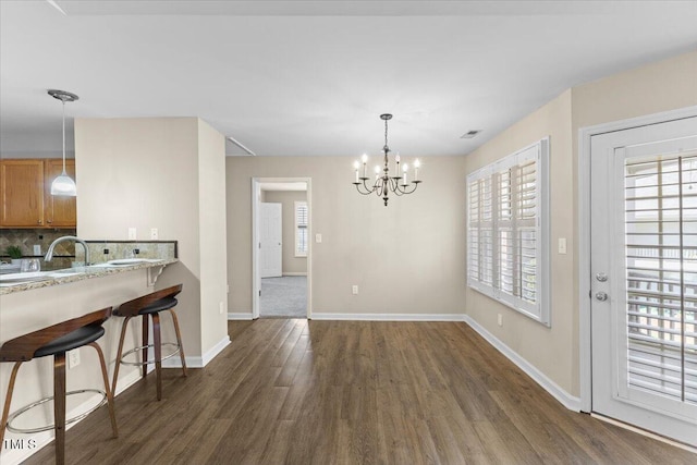 dining area featuring an inviting chandelier, visible vents, baseboards, and dark wood-style flooring