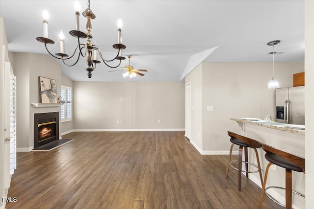 living room featuring visible vents, baseboards, a glass covered fireplace, dark wood-style floors, and vaulted ceiling