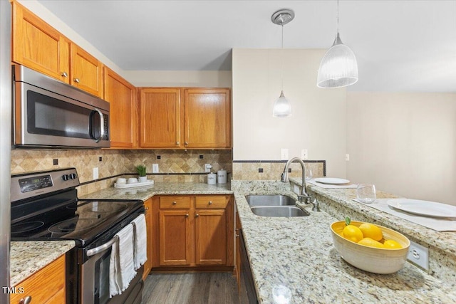 kitchen featuring a sink, appliances with stainless steel finishes, decorative backsplash, light stone countertops, and brown cabinetry