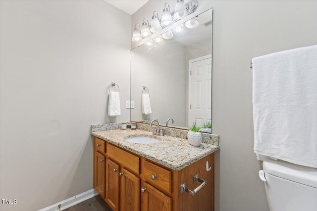 half bath featuring vanity, toilet, and baseboards