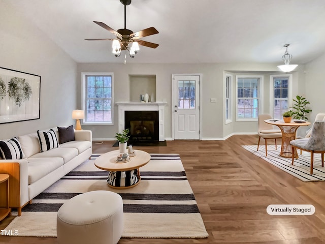 living room with a fireplace with flush hearth, plenty of natural light, wood finished floors, and baseboards