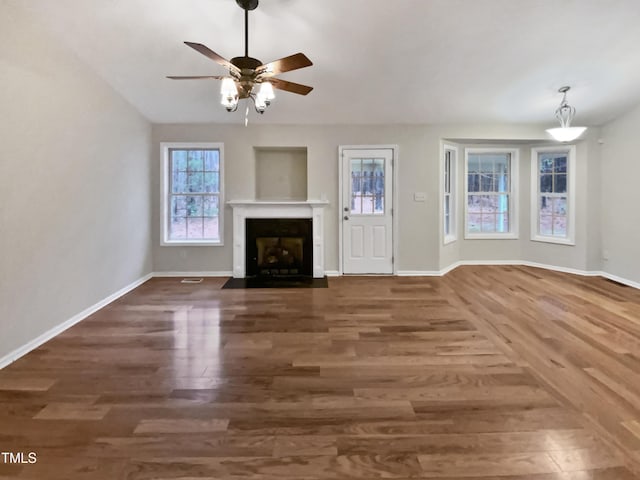 unfurnished living room with a ceiling fan, a fireplace with flush hearth, baseboards, and wood finished floors