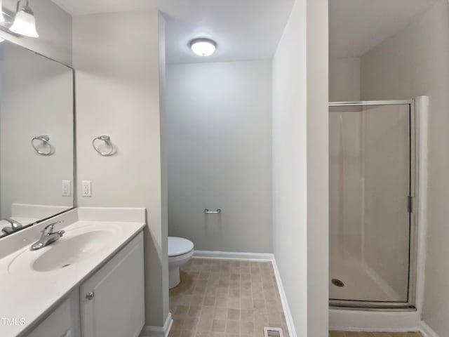 full bath featuring vanity, a shower stall, toilet, and baseboards