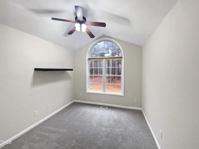 carpeted spare room with lofted ceiling, baseboards, visible vents, and ceiling fan