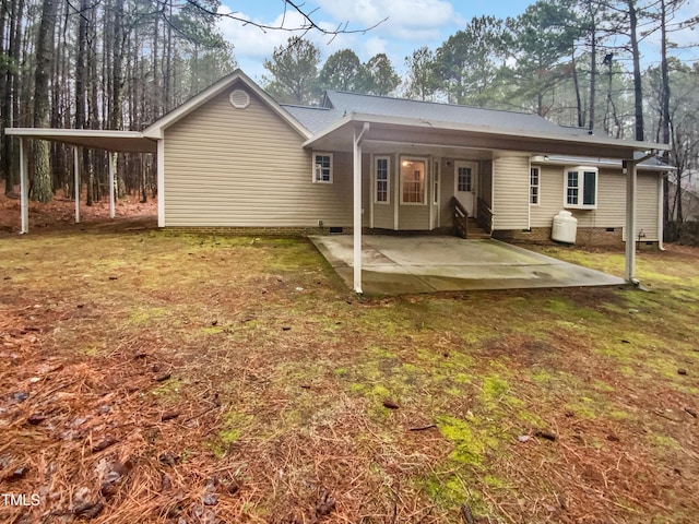 back of house featuring an attached carport, crawl space, a patio area, and a yard