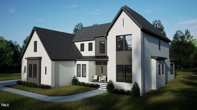 view of front facade featuring roof with shingles, a front lawn, and brick siding