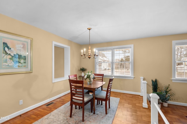 dining space with a notable chandelier, light wood-style floors, visible vents, and baseboards