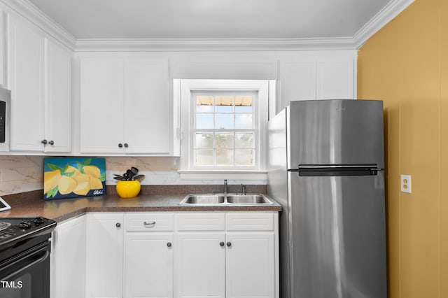 kitchen featuring dark countertops, ornamental molding, freestanding refrigerator, a sink, and black gas stove