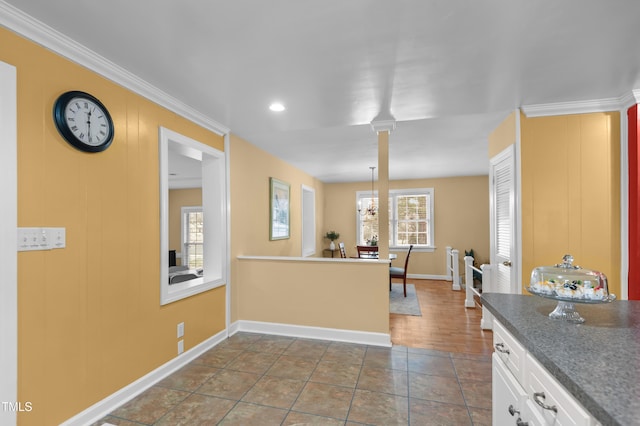 kitchen featuring crown molding, dark tile patterned flooring, white cabinets, and decorative columns