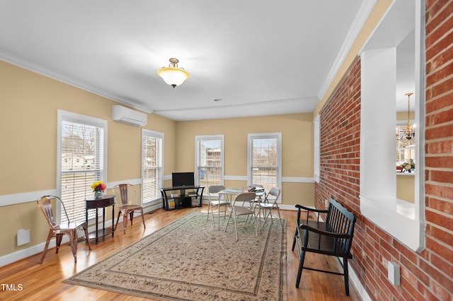 living area featuring an inviting chandelier, brick wall, an AC wall unit, and wood finished floors