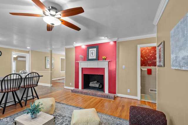 living area with crown molding, a fireplace, baseboards, and wood finished floors