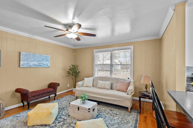 living room featuring ornamental molding, wood finished floors, a ceiling fan, and baseboards