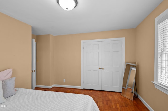 bedroom with a closet, wood finished floors, and baseboards