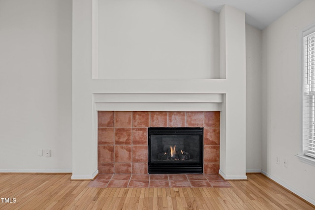 room details with wood finished floors, baseboards, and a tile fireplace