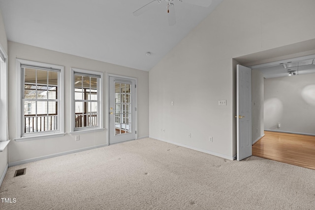 carpeted empty room with high vaulted ceiling, a ceiling fan, visible vents, and baseboards