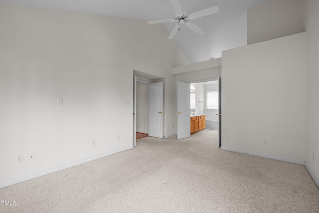 empty room featuring baseboards, light colored carpet, ceiling fan, and high vaulted ceiling