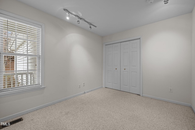 unfurnished bedroom with visible vents, carpet floors, multiple windows, and baseboards