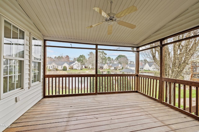 unfurnished sunroom featuring a residential view, wood ceiling, lofted ceiling, and ceiling fan