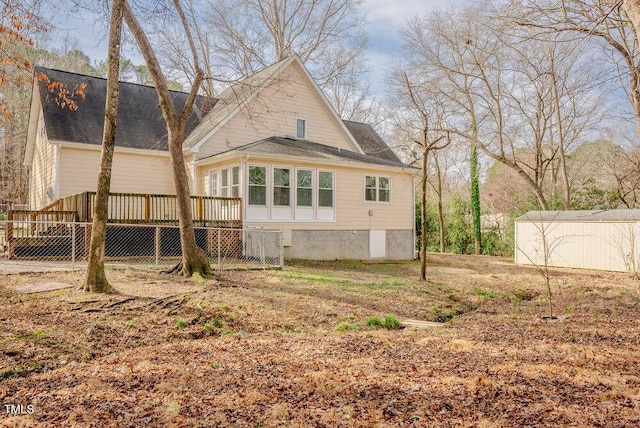 back of house with a deck, a storage shed, and an outbuilding