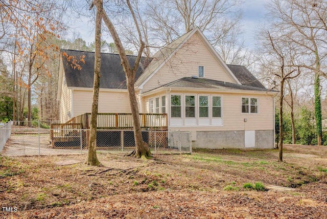 rear view of property with a shingled roof, fence, and a wooden deck