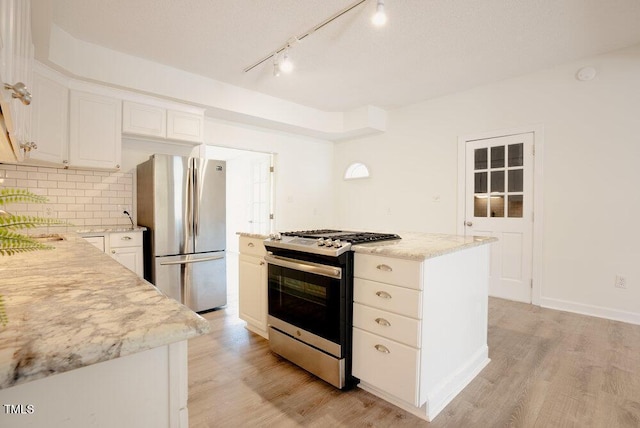 kitchen featuring appliances with stainless steel finishes, white cabinetry, light wood finished floors, and tasteful backsplash