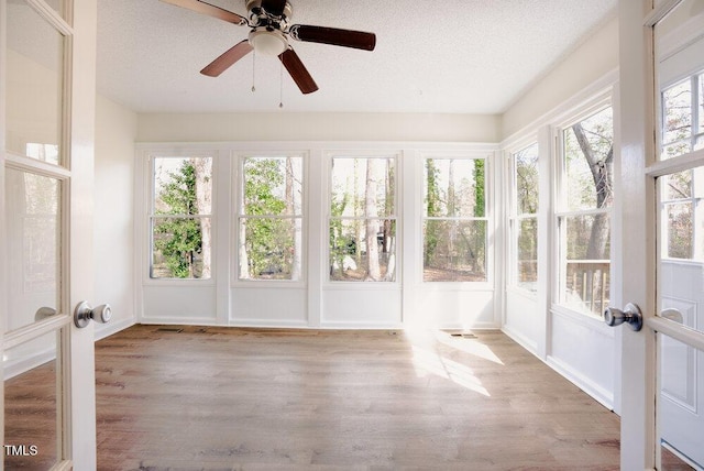 unfurnished sunroom with a ceiling fan and french doors