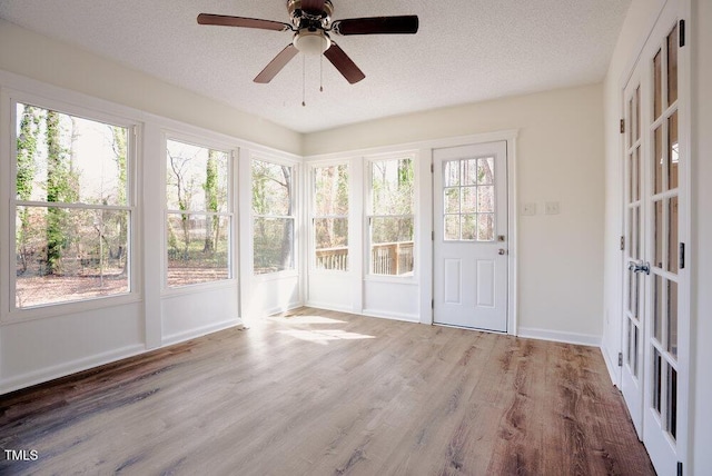 unfurnished sunroom with ceiling fan