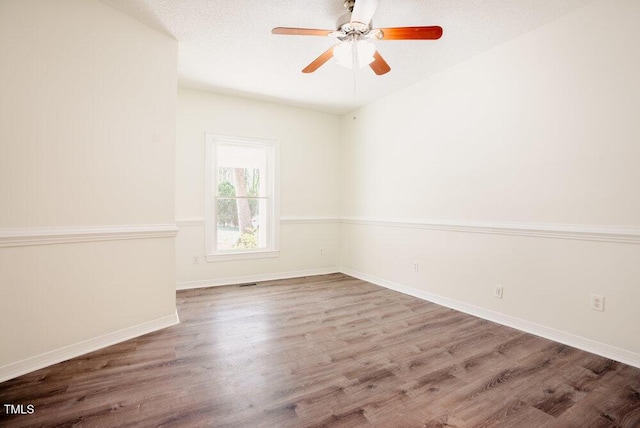 spare room featuring visible vents, baseboards, a ceiling fan, wood finished floors, and a textured ceiling