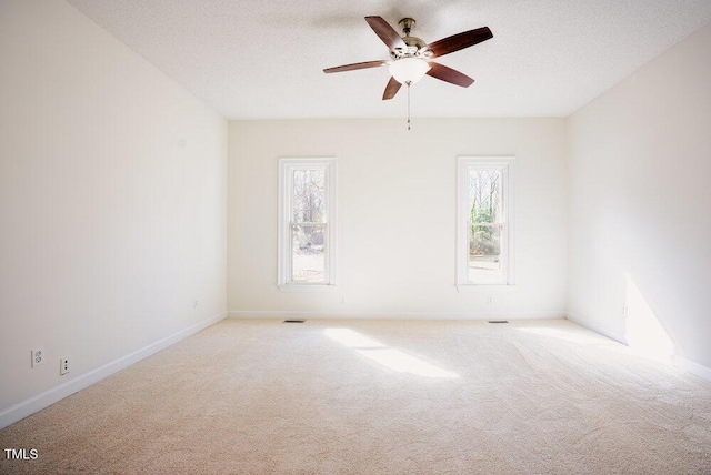 carpeted spare room featuring a ceiling fan, baseboards, visible vents, and a textured ceiling