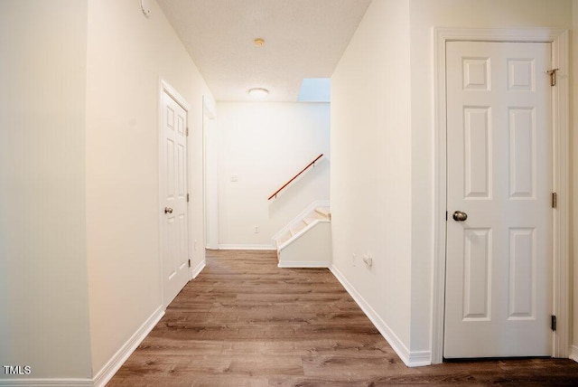 corridor with stairway, baseboards, and wood finished floors