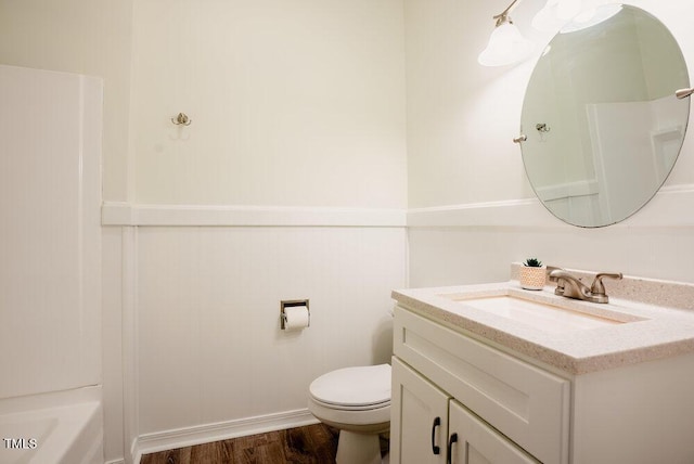 full bath with toilet, a tub to relax in, wood finished floors, and vanity