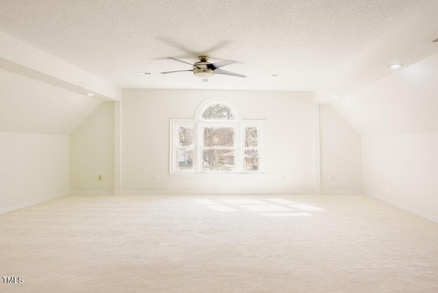 bonus room featuring a textured ceiling, lofted ceiling, and light colored carpet